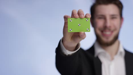 Young-and-handsome-man-smiling-and-presenting-a-buisness-card-into-the-camera