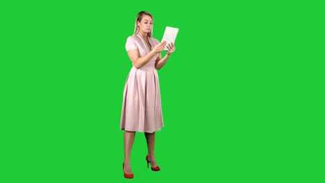 Single-girl-making-a-video-call-on-her-tablet-side-view-full-lenth-on-a-Green-Screen,-Chroma-Key
