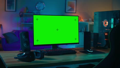 Powerful-Personal-Computer-Gamer-Rig-with-Mock-Up-Green-Screen-Monitor-Stands-on-the-Table-at-Home.-Cozy-Room-with-Modern-Design-is-Lit-with-Warm-and-Neon-Light.