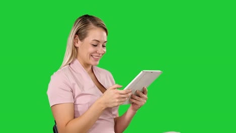 Woman-sitting-watching-tablet-pc-and-smiling-on-a-Green-Screen,-Chroma-Key