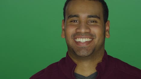 Young-African-American-man-smiling-and-nodding-his-head,-on-a-green-screen-studio-background