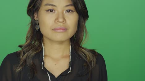 Young-Asian-woman-looking-sad,-on-a-green-screen-studio-background