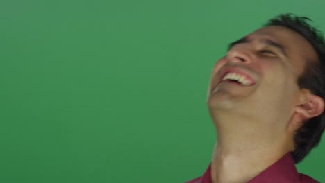 Ethnic-man-laughing-and-smiling,-on-a-green-screen-studio-background