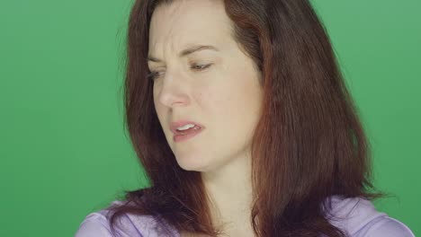 Young-redhead-woman-looking-sad,-on-a-green-screen-studio-background