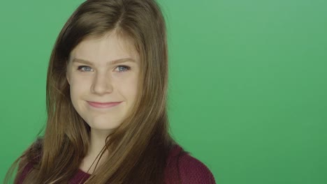 Young-brunette-woman-posing-and-smiling,-on-a-green-screen-studio-background