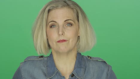 Beautiful-older-woman-seriously-staring,-on-a-green-screen-studio-background