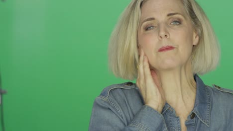 Beautiful-older-woman-suffering-a-headache-and-looking-worried,-on-a-green-screen-studio-background