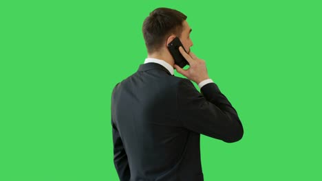 Tiro-medio-de-un-guapo-empresario-Serious-Minded,-hablar-por-teléfono.-Su-fondo-es-pantalla-verde.