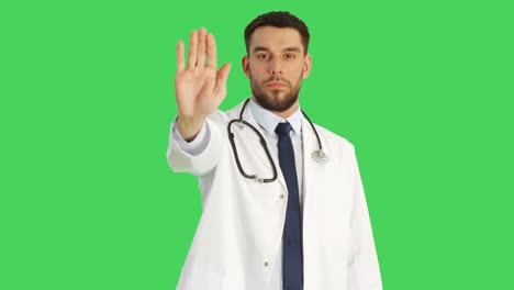 Mid-Shot-of-a-Serious-Minded-Doctor-Making-Stop-Sign-Gesture-with-His-Hand-then-Crossing-Arms-on-a-Chest.-Shot-Taking-Place-with-Green-Screen-Background.