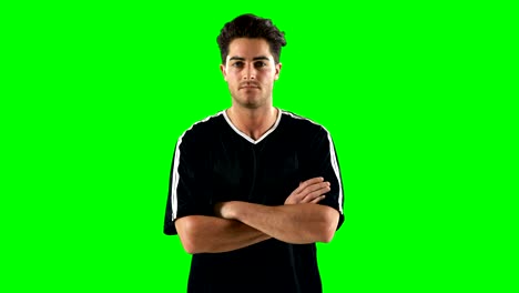 Confident-football-player-standing-against-green-screen