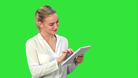 Schöne-junge-Frau-lachend-beim-betrachten-digital-Tablette-auf-einem-Green-Screen,-Chroma-Key