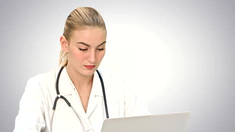 Serious-female-doctor-working-on-her-laptop-computer-on-white-background