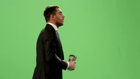 Müde-Geschäftsmann-im-Anzug-ist-zu-Fuß-mit-einem-Kaffee-auf-ein-Mock-up-green-Screen-im-Hintergrund.