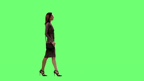 Mujer-morena-glamorosa-en-un-Vestido-ajustado-con-un-monedero-pequeño-caminar-elegantemente-sobre-una-maqueta-verde-pantalla-de-fondo.