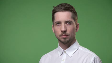 Serious-young-man-in-a-white-shirt-turns-his-head,-chroma-key-green-screen-background