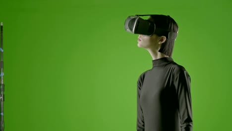 Attraktives-Mädchen-junge-Mode-Modell-tragen-eine-VR-Kopfhörer-in-green-Screen-gedreht