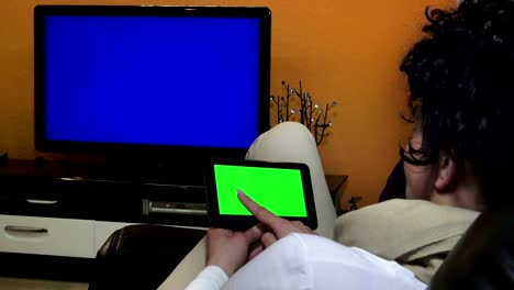 Back-view-of-woman-at-home-using-electronic-tablet-and-smart-tv.-UHD-stock-video,-alpha-matte-included