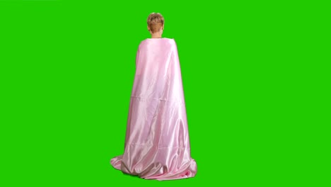 Pretty-girl-in-pink-satin-bedsheet-poses-for-camera-at-green-background