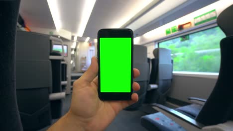 Hand,-die-eine-Handy-mit-einem-Green-Screen-auf-dem-Zug