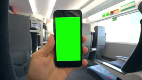 Mano-sosteniendo-un-teléfono-con-una-pantalla-verde-en-el-tren