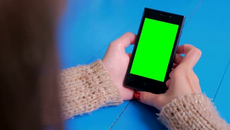 Woman-looking-at-smartphone-with-green-screen