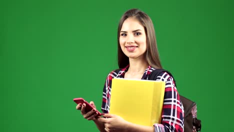 Attractive-young-female-student-using-her-smart-phone-smiling-to-the-camera