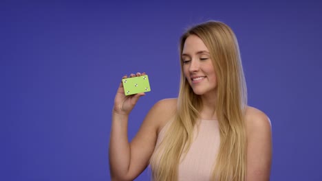 Portrait-of-a-beautiful-Woman-holding-a-blank-Card-into-the-Camera-and-giving-an-stunning-Smile