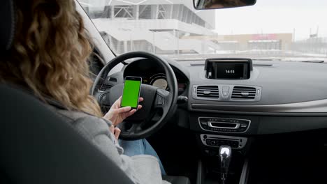 Woman-sits-in-the-modern-car-and-works-on-smartphone---closeup-hands.-Green-screen.Chroma-key