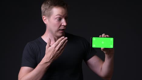 Surprised-Man-Holding-Mobile-Phone-With-Chroma-Key-Green-Screen