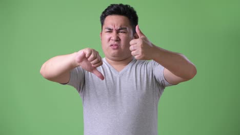 Young-handsome-overweight-Asian-man-against-green-background