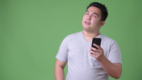 Young-handsome-overweight-Asian-man-against-green-background