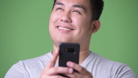 Young-handsome-overweight-Asian-man-against-green-background