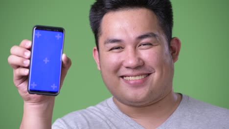 Young-handsome-overweight-Asian-man-against-green-background