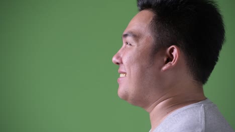 Young-handsome-overweight-Asian-man-against-green-background