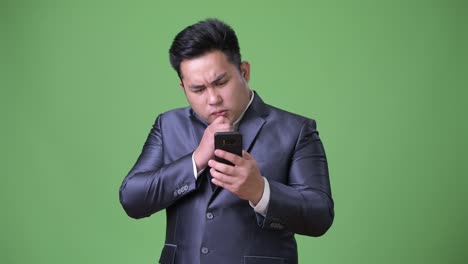 Young-handsome-overweight-Asian-businessman-against-green-background