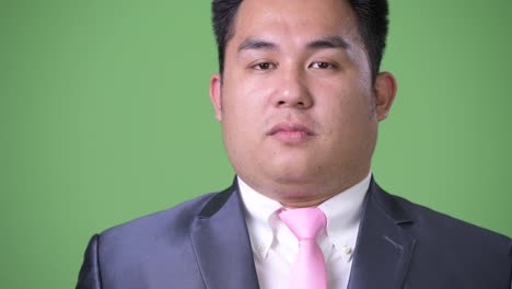 Young-handsome-overweight-Asian-businessman-against-green-background