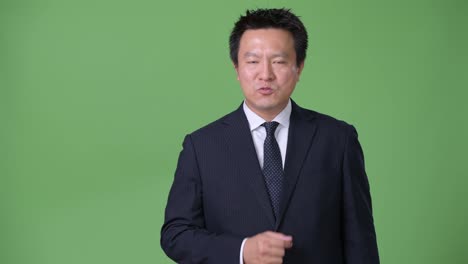 Mature-Japanese-businessman-against-green-background