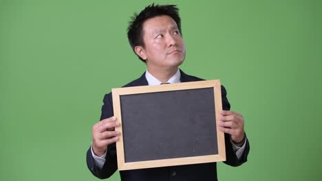 Mature-Japanese-businessman-against-green-background