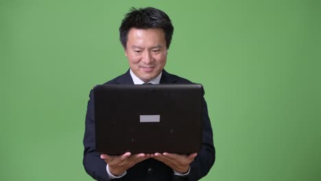 Mature-Japanese-businessman-against-green-background