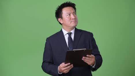 Mature-Japanese-businessman-against-green-background