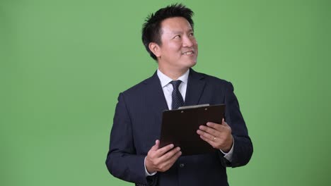 Mature-Japanese-businessman-against-green-background