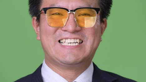 Mature-Japanese-businessman-against-green-background