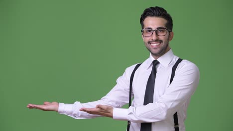 Young-handsome-bearded-Persian-businessman-against-green-background