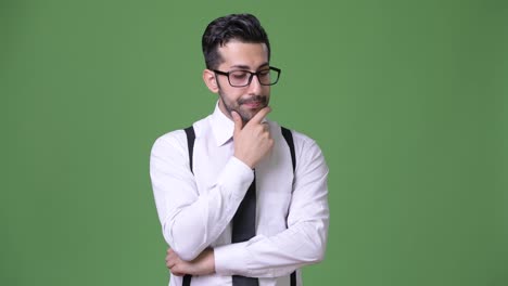 Young-handsome-bearded-Persian-businessman-against-green-background