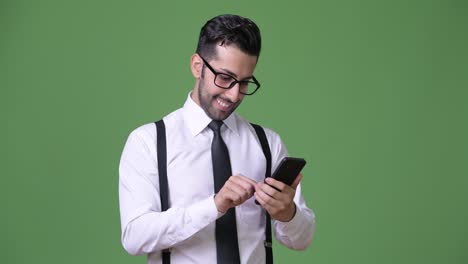 Young-handsome-bearded-Persian-businessman-against-green-background