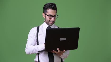 Young-handsome-bearded-Persian-businessman-against-green-background