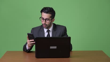 Young-handsome-bearded-Persian-businessman-against-green-background