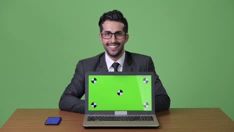 Young-handsome-bearded-Persian-businessman-against-green-background