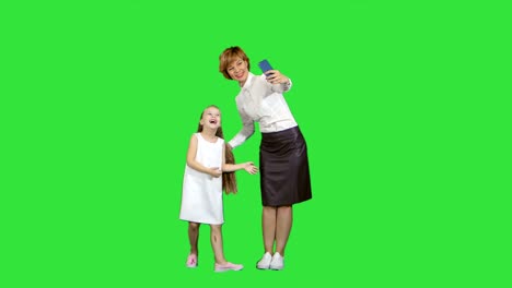 Lächelnde-Mutter-Tochter-Bindung-zusammen,-um-ein-Selbstporträt-auf-einem-Green-Screen,-Chroma-Key-nehmen