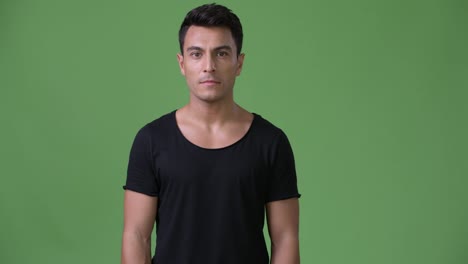 Young-handsome-Hispanic-man-against-green-background